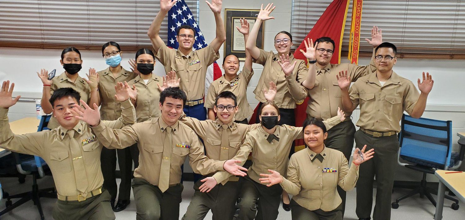SY22-23.Staff Group of smiling people in matching tan uniforms posing indoors.